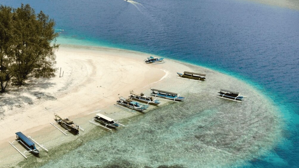 A beach with boats and a clear blue sea. 1