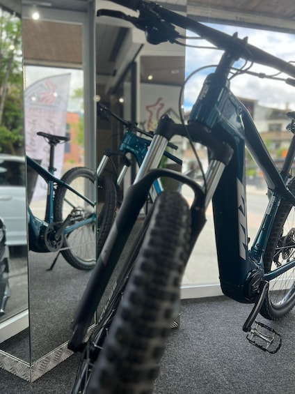 A bicycle inside a store with a glass door reflecting another bicycle outside. 2