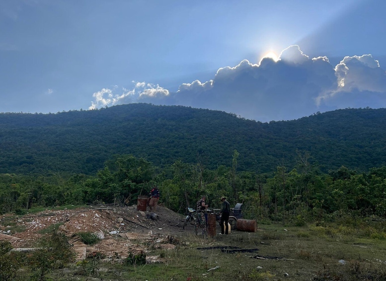 A hilly landscape with a group of people and a motorcycle near a pile of debris. 3