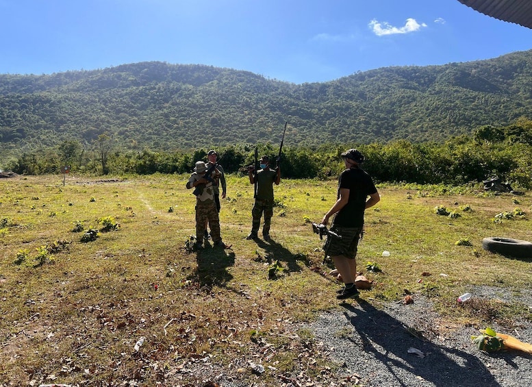 A group of people in a grassy field with mountains in the background. 2