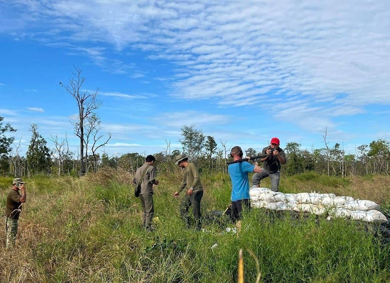 A group of people in a grassy field with trees and a clear sky. 1