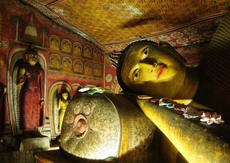 A large golden Buddha statue in a temple with intricate architecture and smaller statues. 3