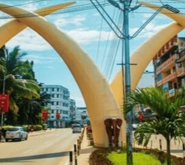 A street with large, curved structures, palm trees, and buildings in the background. 3