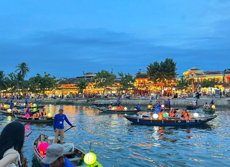 A river with boats and people, illuminated buildings, and palm trees. 4