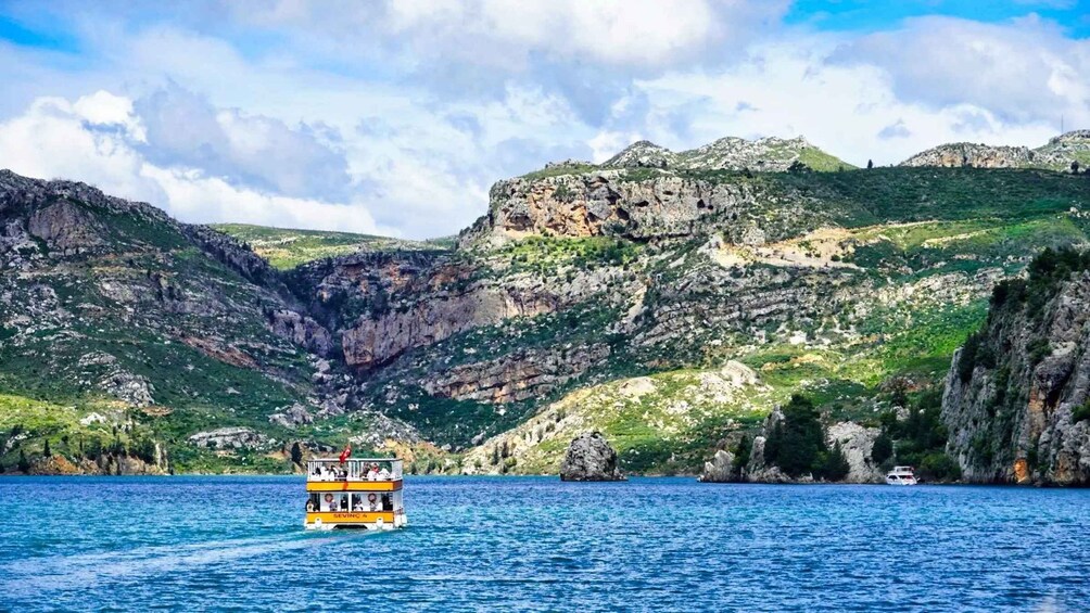 A boat named 'SEVINC 4' on a calm sea with a mountainous landscape in the background. 2