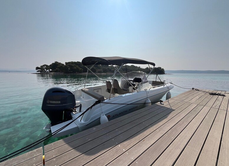 A boat docked on a wooden pier with clear water and a small island in the background. 4
