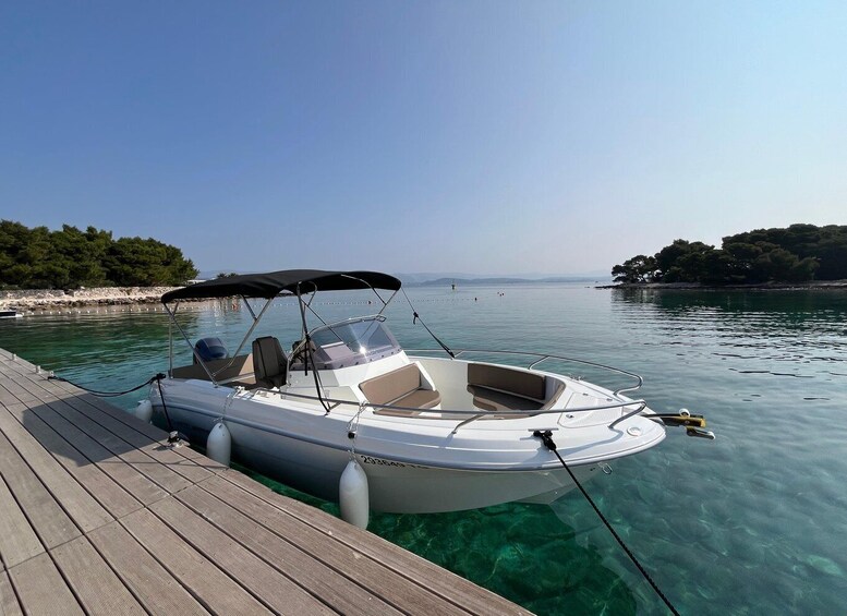 A small motorboat docked at a wooden pier with clear turquoise water. 3
