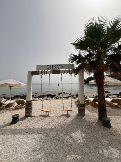 A beach with a swing set labeled "SHKOY," palm trees, and lounge chairs. 5