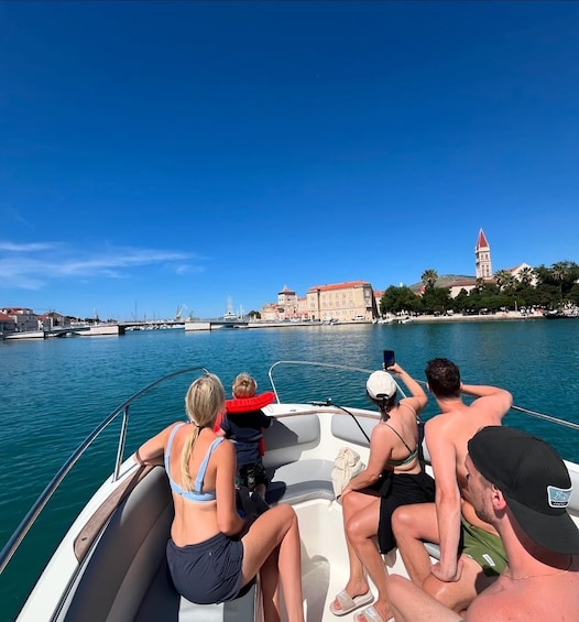 A group of people on a boat in a body of water with a cityscape in the background. 1