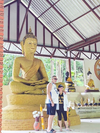 A large golden Buddha statue, a man and a woman in sports attire, and traditional Thai architecture. 4