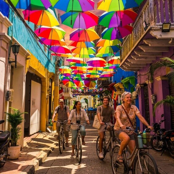 A street with colorful umbrellas overhead and people riding bicycles. 2
