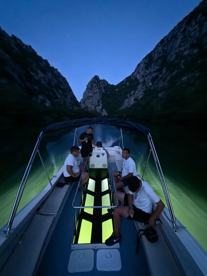 A boat with people on board, surrounded by rocky cliffs and water. 4