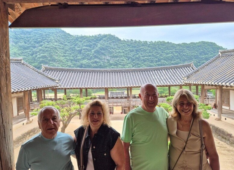 A group of people in front of traditional Korean architecture with a mountainous landscape in the background. 5