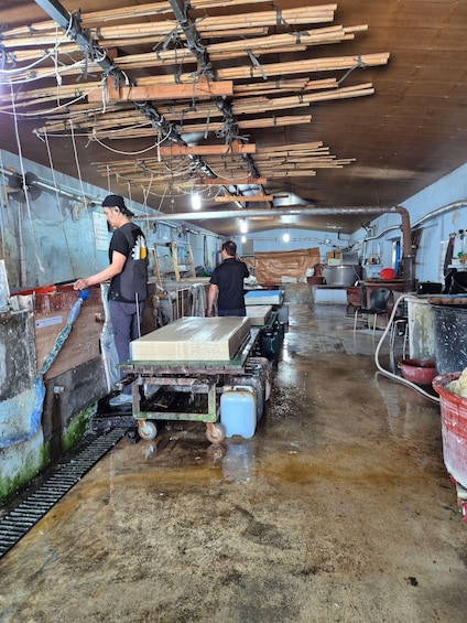 A wet, industrial kitchen with workers, wooden planks, and a cart. 2