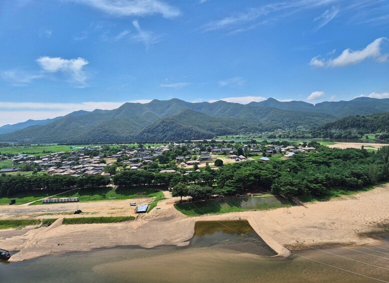 A rural village with houses, a river, and mountains in the background. 4