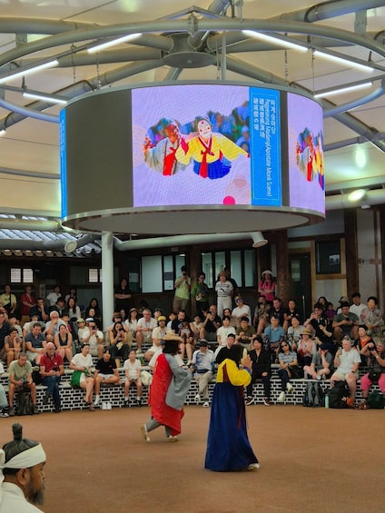 A performance with two individuals in traditional attire in front of a large audience. 3