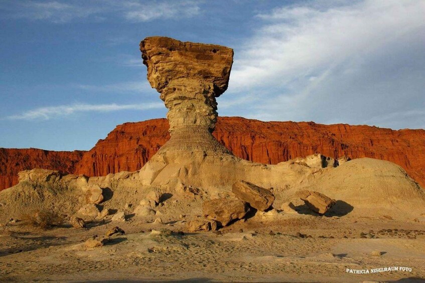 A rock formation with a prominent vertical pillar in a desert landscape. 3