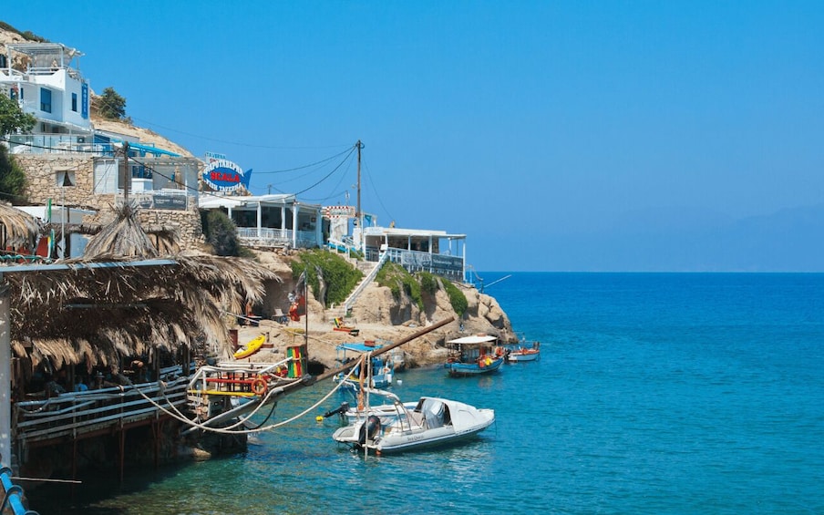 A coastal town with buildings, a pier, boats, and clear blue sea. 3