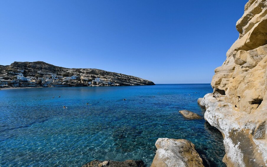 A coastal town with clear blue waters, rocky cliffs, and buildings on a hillside. 5