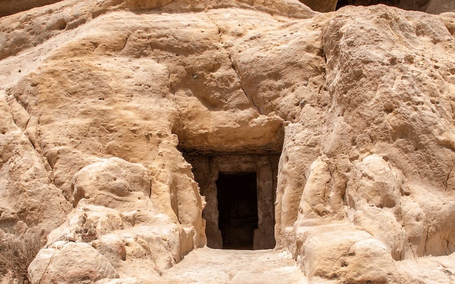 A rock-cut entrance with a narrow passageway leading into a dark interior. 2