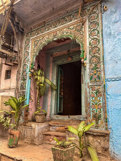 Une entrée de bâtiment richement décorée, ornée de sculptures florales complexes et dont la porte est entrouverte. 3