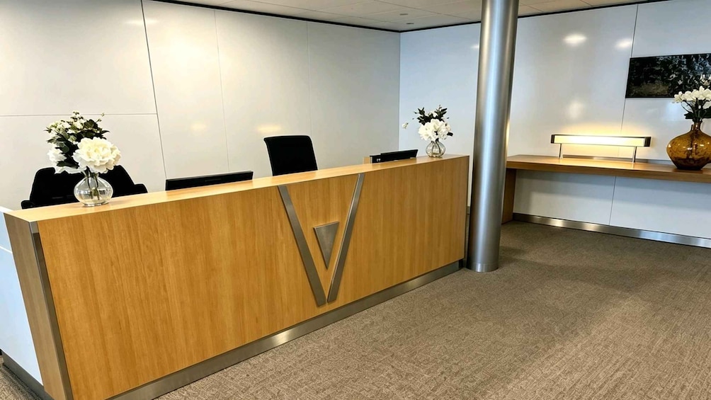 A reception desk with two vases of white flowers, a modern interior, and a large pillar. 1