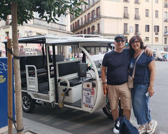 A man and a woman standing next to a white vehicle with a sign that reads "MADRID". 5