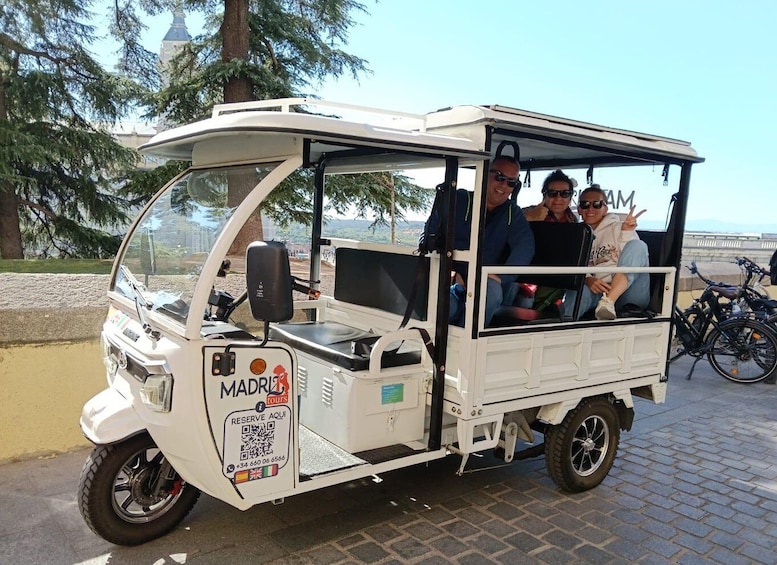 A white three-wheeled vehicle with a roof, labeled 'MADRID TOURS'. 1