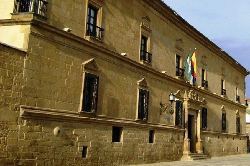 A historic building with a stone facade, multiple windows, and flags. 2