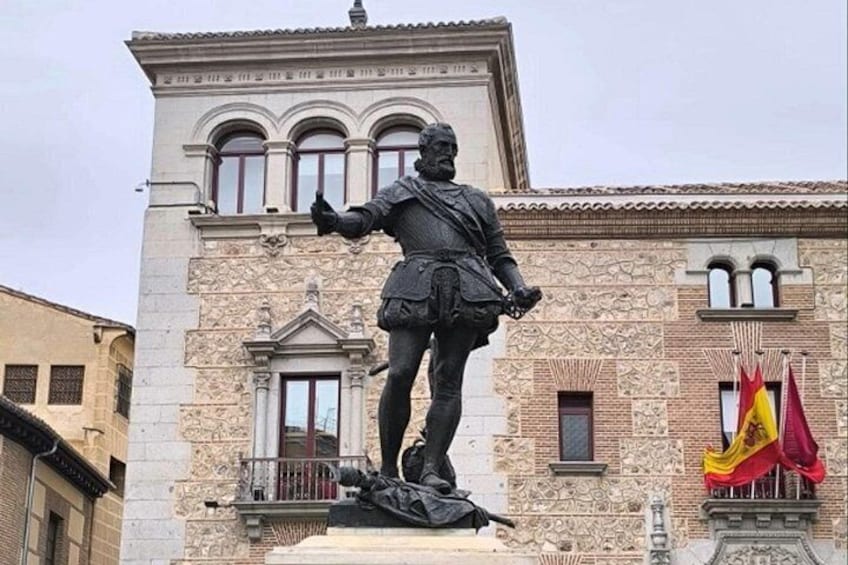 A statue of a historical figure in military attire, a building with classical architecture, and two flags. 4