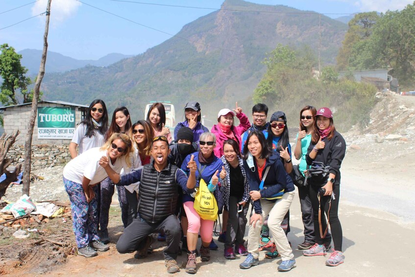 A group of people posing for a photo in a mountainous area with a sign that reads "TUBORG". 1