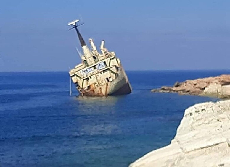 A shipwreck in the sea near a rocky coastline. 3