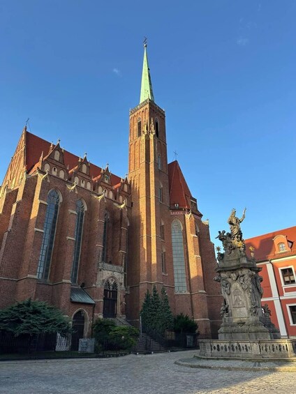 A historic church with a tall spire and a statue in front. 4