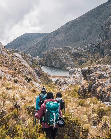 A group of hikers on a rocky trail with a lake in the background. 3