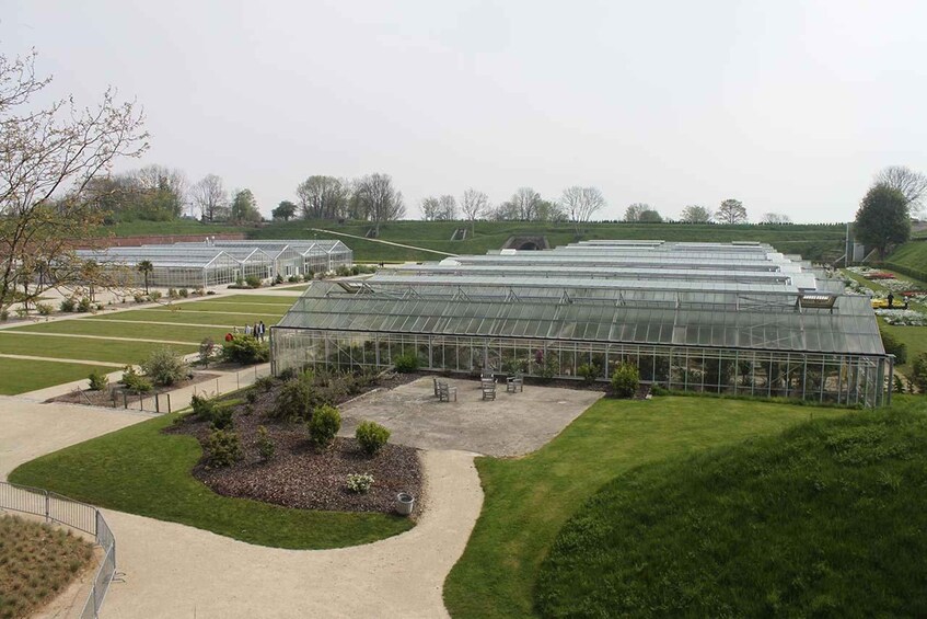 A large greenhouse complex with multiple sections, surrounded by landscaped gardens and pathways. 2