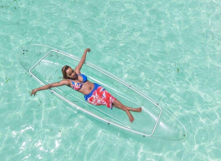 A person lying on a transparent floatation device in clear turquoise water. 4
