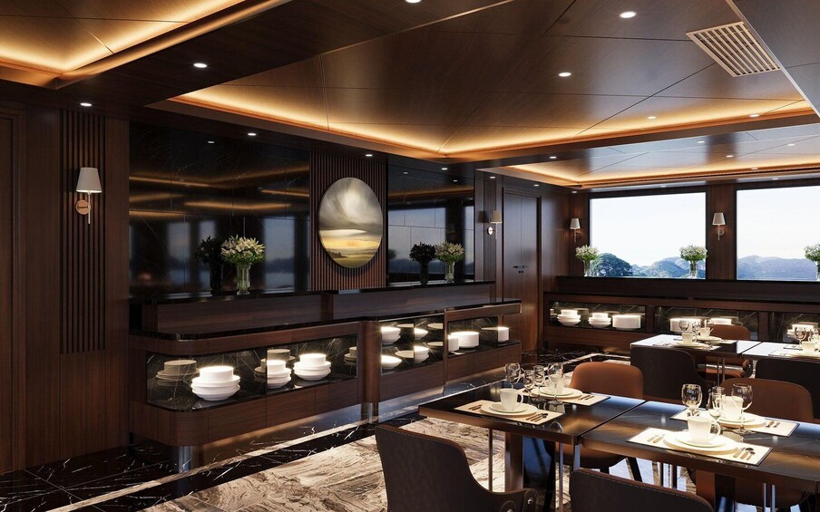 A modern dining area with dark wood paneling, a large oval mirror, and a view of mountains through the windows. 5