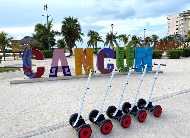 Large colorful letters spelling 'CANCUN' with a row of scooters in front. 2
