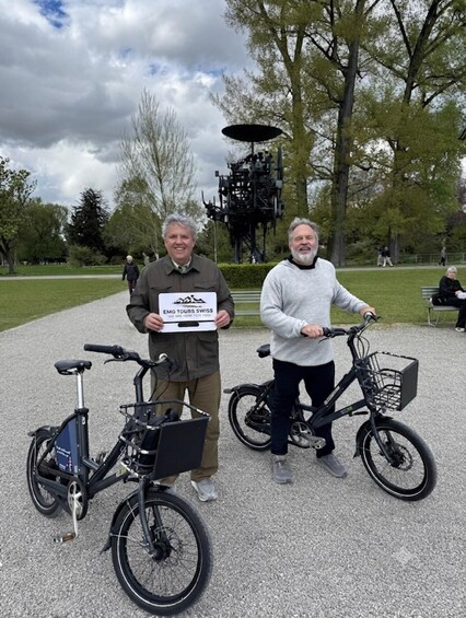 Two people holding a sign, one with a bicycle and another with a bicycle in a park. 3