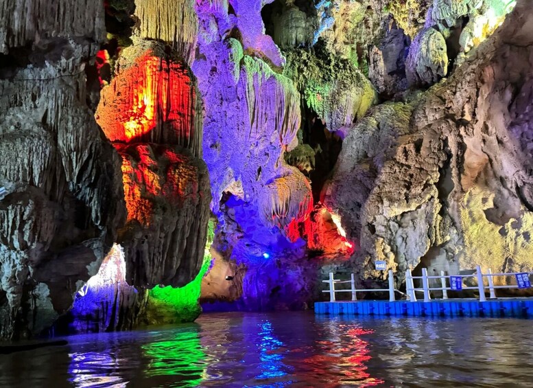 A cave with colorful illuminated stalactites and a water pool reflecting the lights. 2