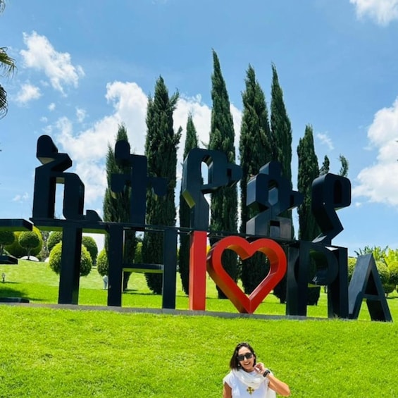 A person standing in front of a sign with abstract shapes and a heart symbol. 1