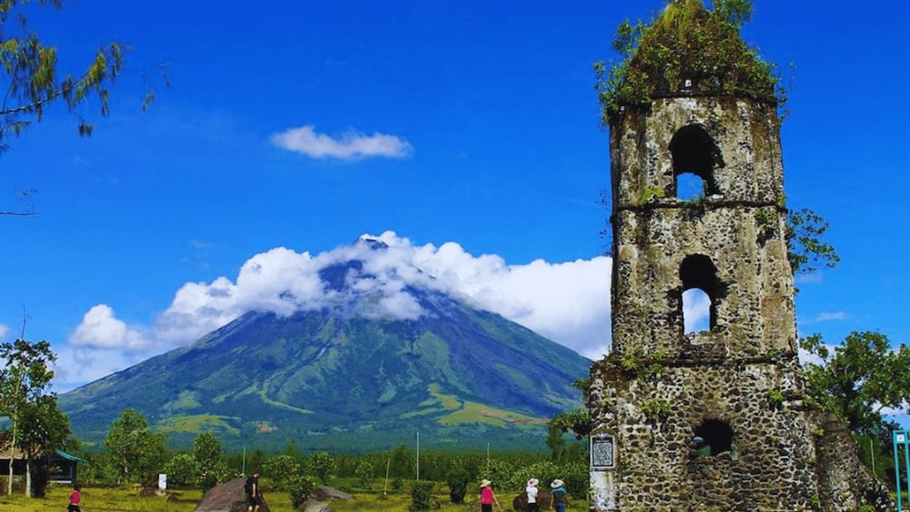 A stone bell tower with a mountain in the background. 2