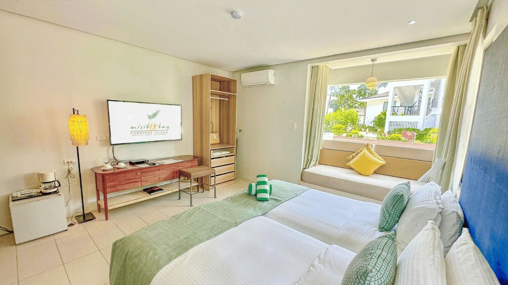 A hotel room with a bed, a desk, a TV, and a window with a view of the outside. 4