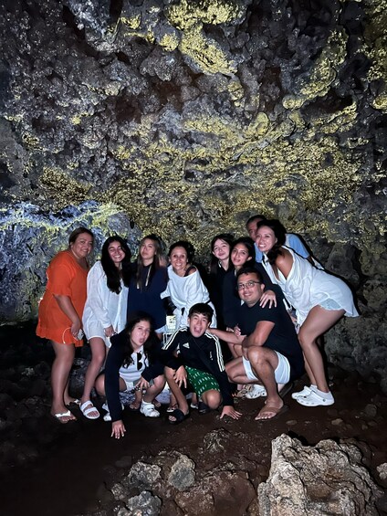 A group of people posing in front of a cave with golden lichen. 3