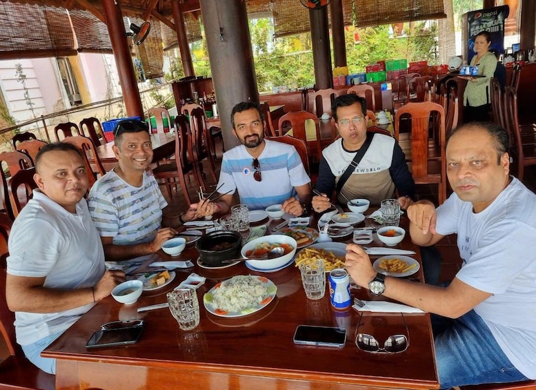 A group of people dining at an outdoor restaurant with various dishes and drinks on the table. 4