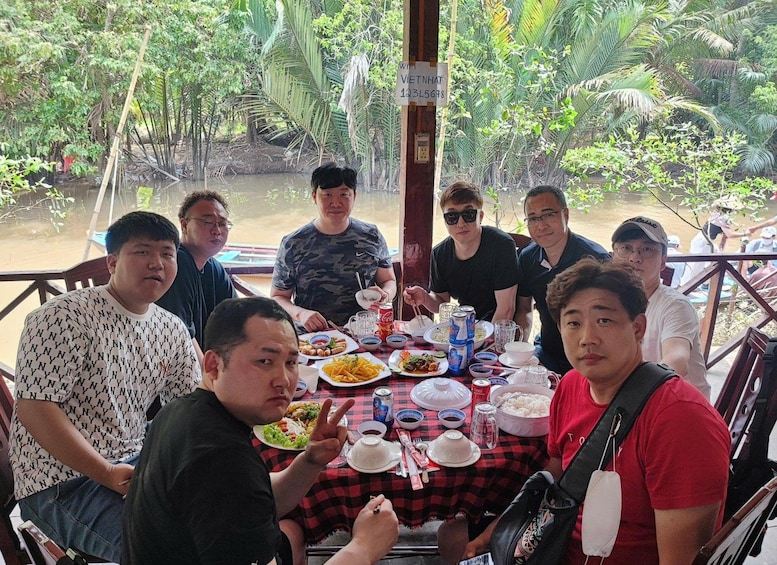 A group of people dining at an outdoor table with various dishes and drinks. 3