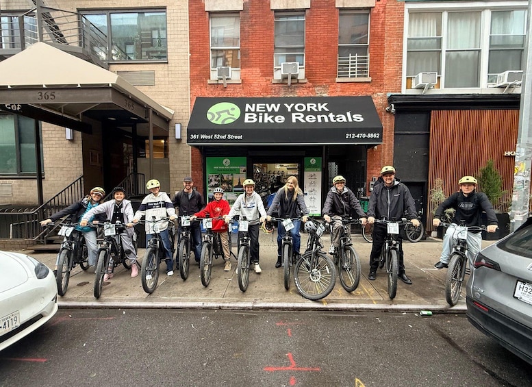 A group of people on bicycles in front of a bike rental shop. 2