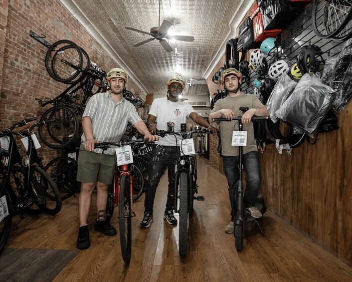 Three people standing in a bicycle shop with various bikes and helmets on display. 5