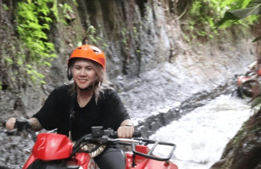 Une personne conduit un quad rouge dans un canyon étroit et rocheux, près d’une rivière. 2