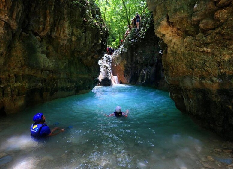 A cave with a waterfall and people swimming. 4